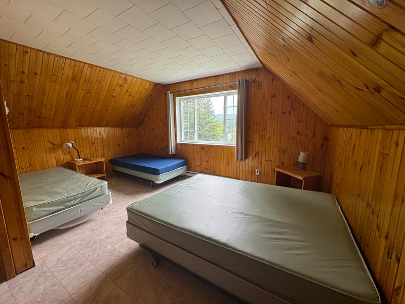Une chambre d'un des Jobin #3 à 10, avec deux lit simple et une lampe entre les deux