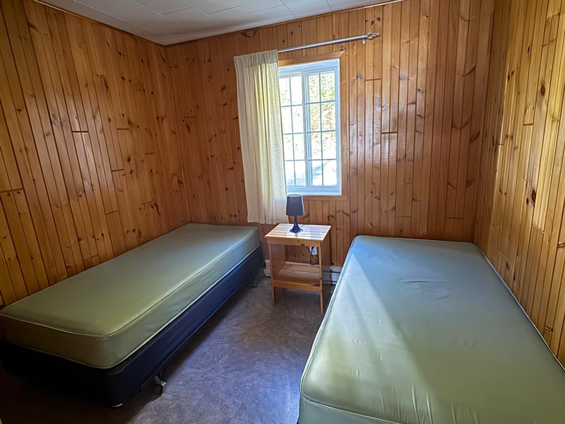Une chambre d'un des Jobin #11 à 14, avec deux lit simple et une lampe entre les deux